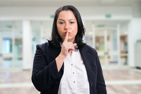 Serious Businesswoman Making Shush Gesture Office Background