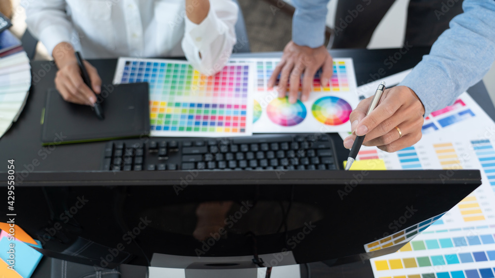 Poster graphic designer team working on web design using color swatches editing artwork using tablet and a 