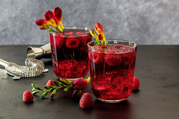 Fresh berries cocktail with gin, raspberry, soda water, and ice in glass on dark background. Summer cold alcohol drink. copy space 