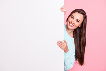 Photo of cheerful young woman hold stand white banner empty space isolated on pastel pink color...