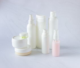 White bottles and cans for cosmetics on a light background. Clean, layout and template