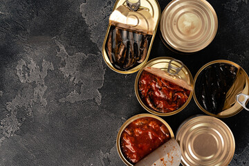 Top view of opened cans with fish conserves on wooden background