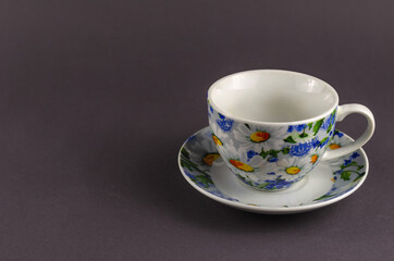 White cup with painted flowers on a gray background.