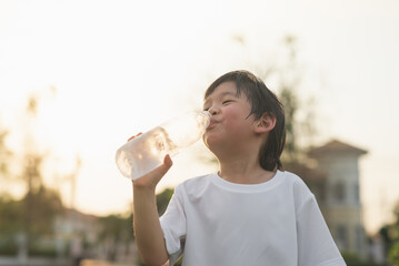 asian boy drinks water from a bottle outdoors