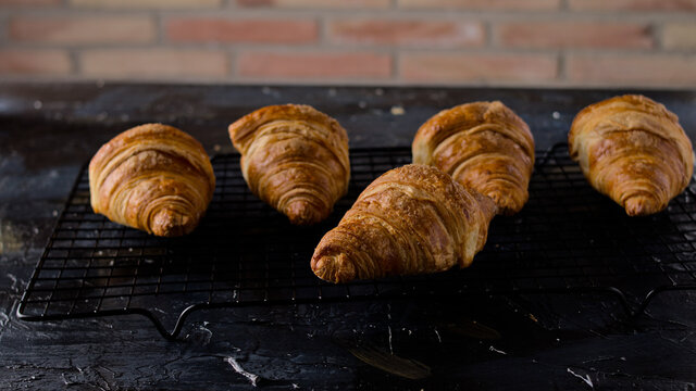 croissant reci&eacute;n horneados enfiandose en una rejilla met&aacute;lica