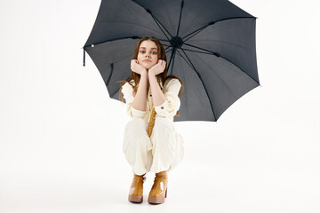 pretty woman with open umbrella squatting fashion studio