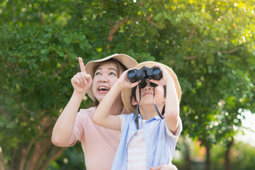 Asian mother and son using binoculars  outdoors in sunny summer day