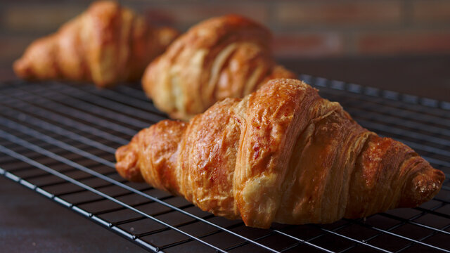 croissant reci&eacute;n horneados enfiandose en una rejilla met&aacute;lica