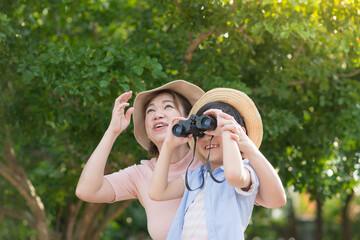 Asian mother and son using binoculars  outdoors in sunny summer day
