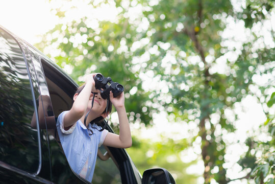 Child Holding Binoculars Out Of The Car Window On Summer Day