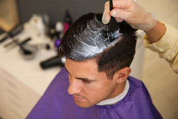 Professional hairdresser dying hair in beauty salon, closeup