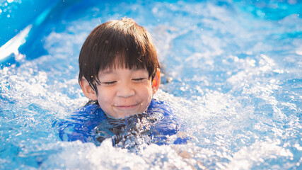 Fototapeta na wymiar Cute Asian boy swimming and playing in a pool