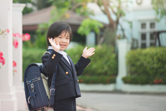 Asian student going to school and waving goodbye,back to school concept,outdoors