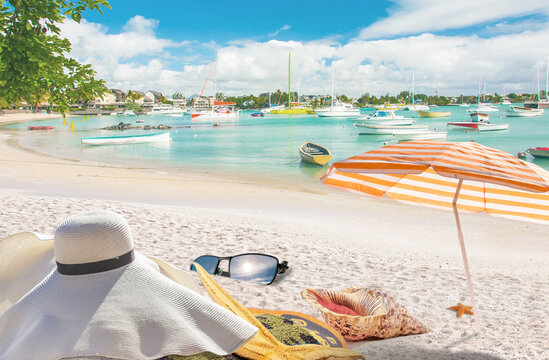 Parasol, chapeau, serviettes, lunettes de soleil et coquillages sur plage de Grand-Baie, île Maurice 