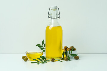 Bottle and bowl with olive oil, olives and twigs on white background
