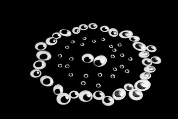 Obraz premium A circle of toy eyes. filled with small eyes on a black background