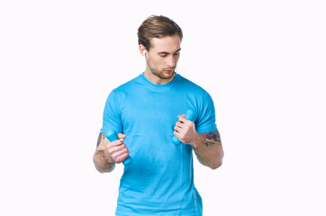 man with dumbbells in a blue t-shirt on a light background looking to the side cropped view