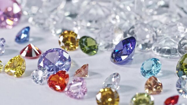 A big pile of colorful gemstones  are placed on white floor with white diamonds background.
