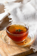 Herbal Thyme tea glass with thymus plant on linen table cloth.