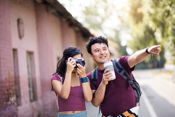 Young couple standing on street. Girl uses a camera.