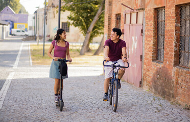 Young couple on the street with bike and electric scooter.
