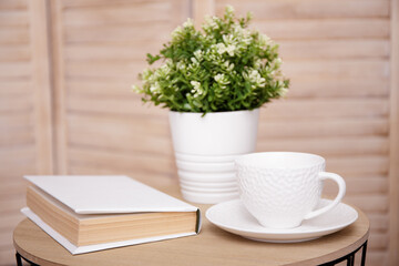 Close up of table with cup, plant and book
