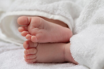 Close-up Shot of a  Four Week Old Baby Boy Crossed Feet Over White Towel.