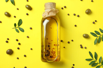 Bottle of olive oil and spices on yellow background