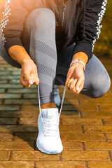 Outdoor Sport Concepts. Active Female Runner Tighten Up Her Shoelaces During Jogging Training Exercise Outdoor.