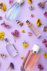 Bottle of perfume with flowers on purple background. Vertical foto