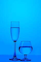 Glassware Ideas. Two Different Glass Cups in One Line With Vivid  Blue Colorful Background.