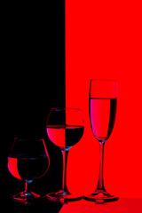 Glassware Ideas. Three Different in Height Glass Cups Placed in One Line Against Vivid  Black And Red Background.