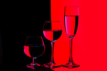Glassware Ideas. Three Different in Height Glass Cups Placed in One Line Against Vivid  Black And Red Background.