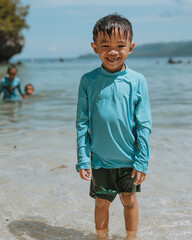 Fototapeta na wymiar Cute and Happy Little Kid having Fun on White Sand Beach. Smiling into the Camera