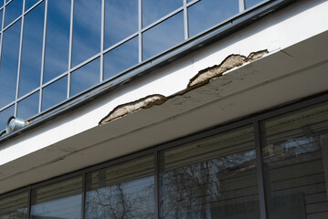 Collapsing building facade, outside close-up. Business office, destroyed cement masonry