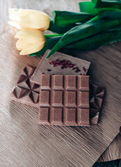 Handmade pink chocolate with raspberries. Vegetarian chocolate with berries on a wooden table and pink paper. A pink little bucket with yellow yellow in it. International Women's Day on March 8.
