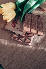 Handmade pink chocolate with raspberries. Vegetarian chocolate with berries on a wooden table and pink paper. A pink little bucket with yellow yellow in it. International Women's Day on March 8.