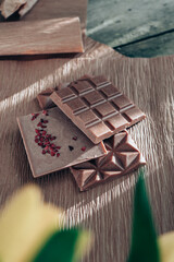 Handmade pink chocolate with raspberries. Vegetarian chocolate with berries on a wooden table and pink paper. A pink little bucket with yellow yellow in it. International Women's Day on March 8.