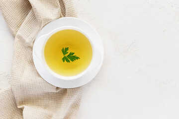 Homemade chicken broth in a white plate on a white table. Horizontal orientation, copy space, top...