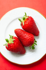 set of 3 strawberries on a plate on red background