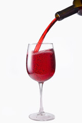 Red wine is poured into a glass from a bottle, isolate on a white background