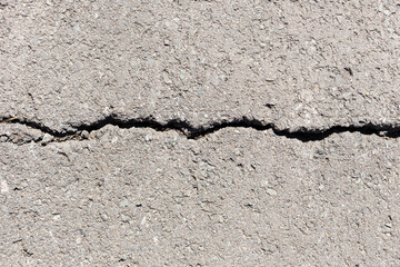 Obraz premium Worn and cracked asphalt with big cracks. Old road concrete texture with cracks