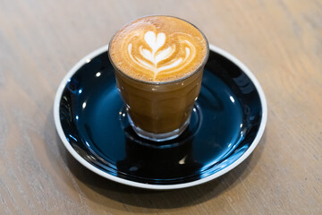 decorated glass of Coffee Piccolo Latte on a white table in a Sydney Cafe NSW Australia