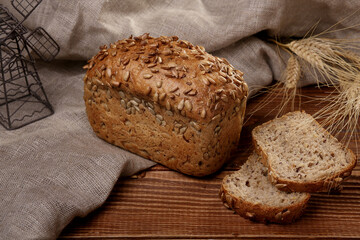 Grain bread with sliced slices on a linen and wooden background