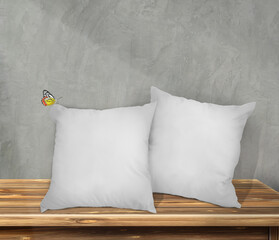 Fototapeta na wymiar Beautiful an idea Mockup Blank white square pillow cotton with butterfly. On a wooden table and on a gray wall