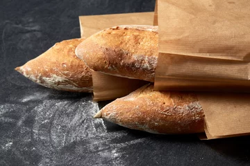 Photo sur Aluminium Boulangerie concept de nourriture, de cuisson et de cuisson - gros plan de pain baguette dans des sacs en papier sur une table sur fond sombre