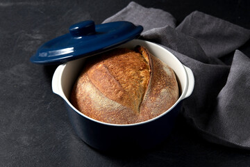 food and cooking concept - homemade craft bread in ceramic baking dish on table
