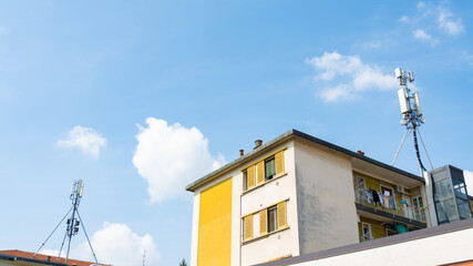5g and 4g antennas on the roof of residential buildings, Milan, Italy. Blue sky on the background