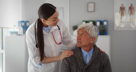 Smiling young female doctor cheering happy senior patient at medical checkup visit