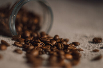 Spilled coffee beans issuing from inside an overturned jar